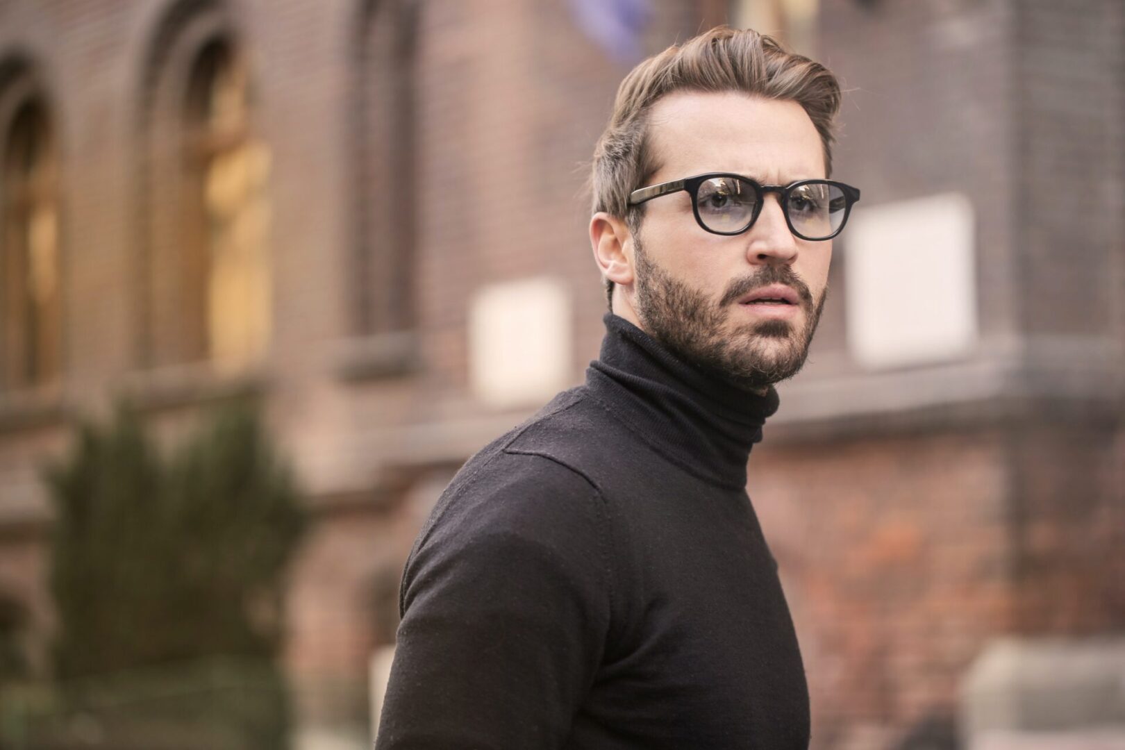 A man with glasses and a beard wearing a black sweater.